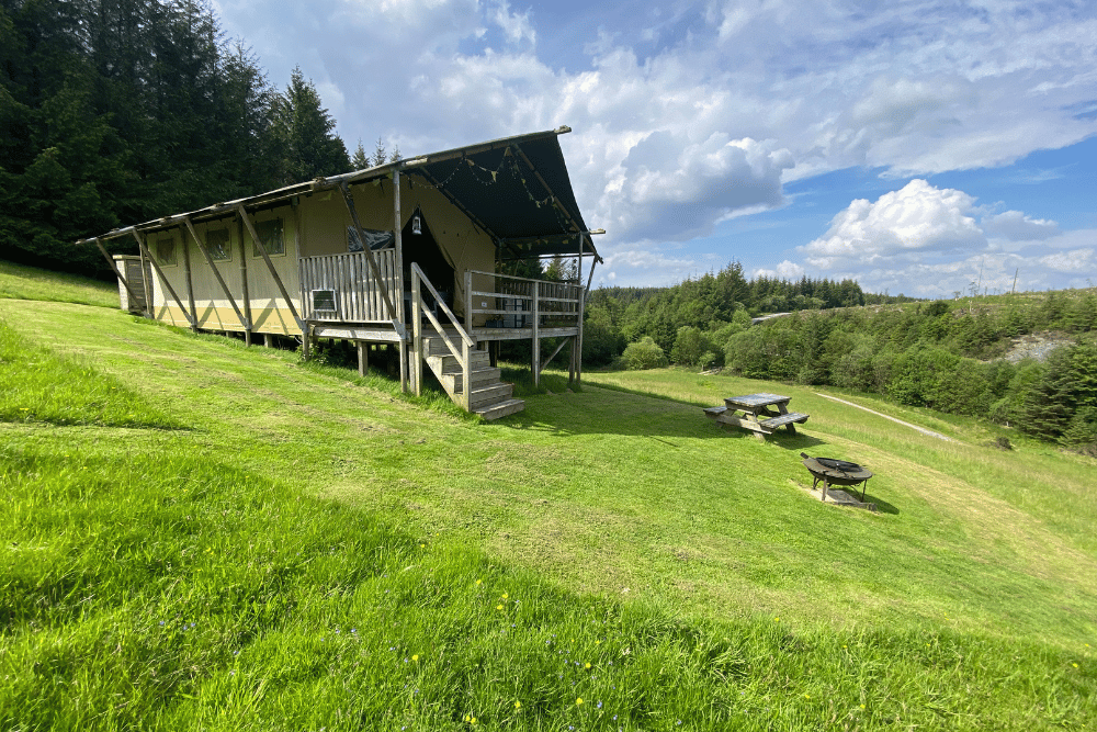 Safari tent in a green field with blue sky